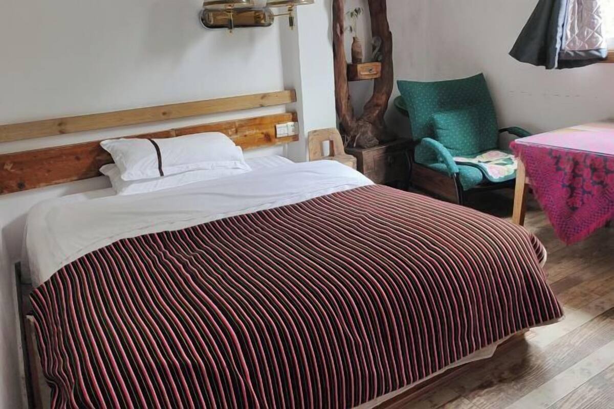 Uma cama com colcha listrada, cabeceira de madeira e mesa de cabeceira com abajur.