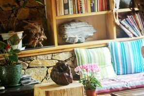 Un angolo accogliente per leggere, con una libreria, uno sgabello in legno e una pianta in vaso.