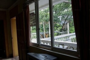 A room with a large window, a bench, and a view of a bridge and trees. - Far Away Inn (Yulong)