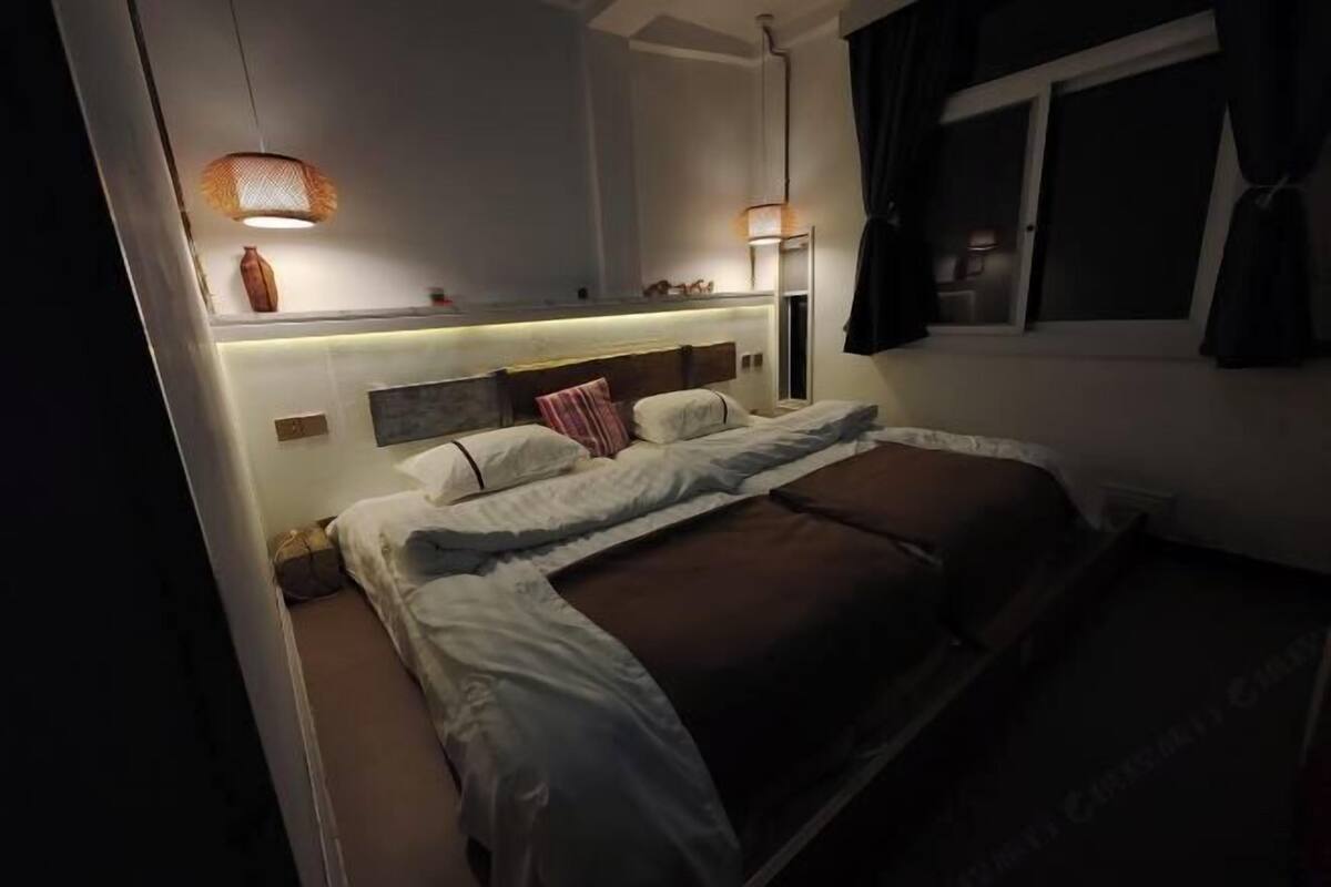 Quarto com cama, luminárias de cabeceira, mesa de cabeceira, janela e espelho.