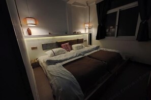 A bedroom with a bed, bedside lamps, a nightstand, a window, and a mirror. - Far Away Inn (Yulong)