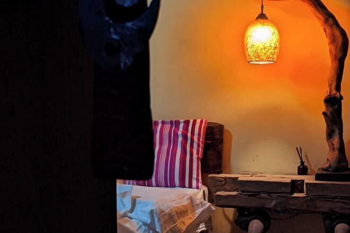 A dimly lit room with a wooden table, a striped pillow, and a hanging light fixture.
