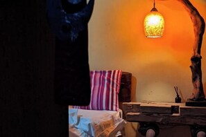 A dimly lit room with a wooden table, a striped pillow, and a hanging light fixture. - Far Away Inn (Yulong)