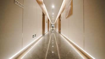 A corridor with a polished floor, wall-mounted light fixtures, and a sign indicating an emergency exit.