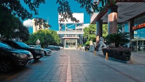 L’entrée d’un hôtel, avec une façade moderne, un espace de stationnement et une statue au premier plan.