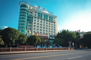 A multi-story hotel with a curved facade, a prominent entrance, and a clear sky.
