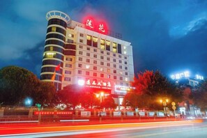 Un hôtel à plusieurs étages, reconnaissable à son grand panneau rouge, à sa façade bien éclairée et à son architecture moderne.