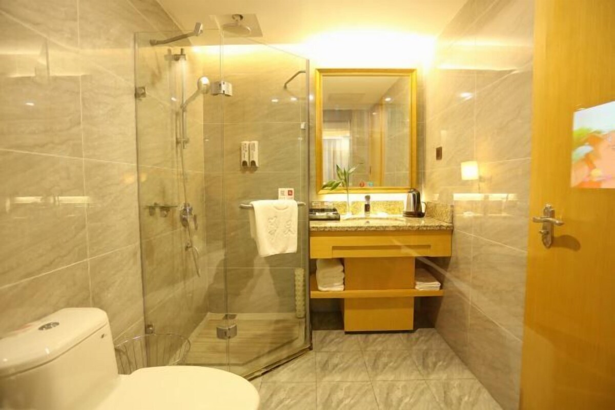 A bathroom with a glass-enclosed shower, a toilet, a sink with a mirror, and a wooden vanity.