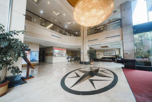 A spacious lobby with a central clock, high ceilings, and a large hanging light fixture.