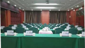 A conference room with rows of tables, each with a nameplate and a cup.