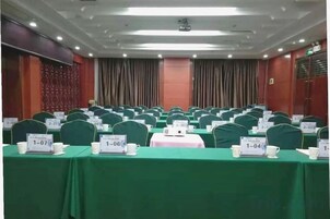 Un salón de conferencias con filas de mesas, cada una con una placa de identificación y una taza.