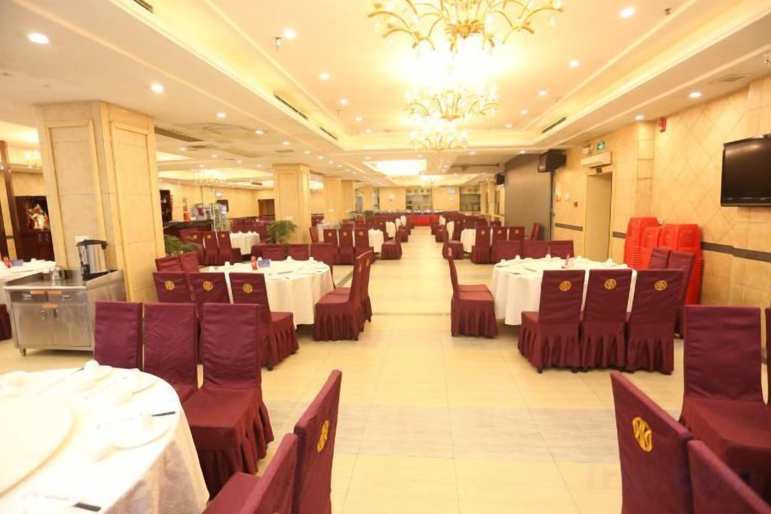 A banquet hall with round tables, chairs, and a chandelier.