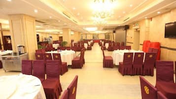 A banquet hall with round tables, chairs, and a chandelier.