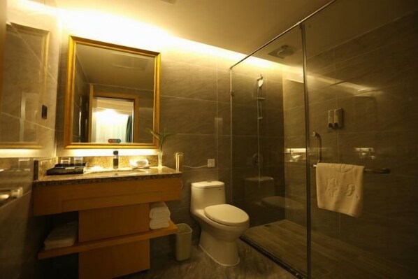 A modern bathroom with a glass shower enclosure, a toilet, and a vanity with a mirror. - Lianhua Hotel (Ningyuan)