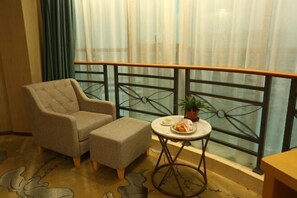 A balcony with a cushioned chair, a small round table with a plate of food, and a potted plant. - Lianhua Hotel (Ningyuan)