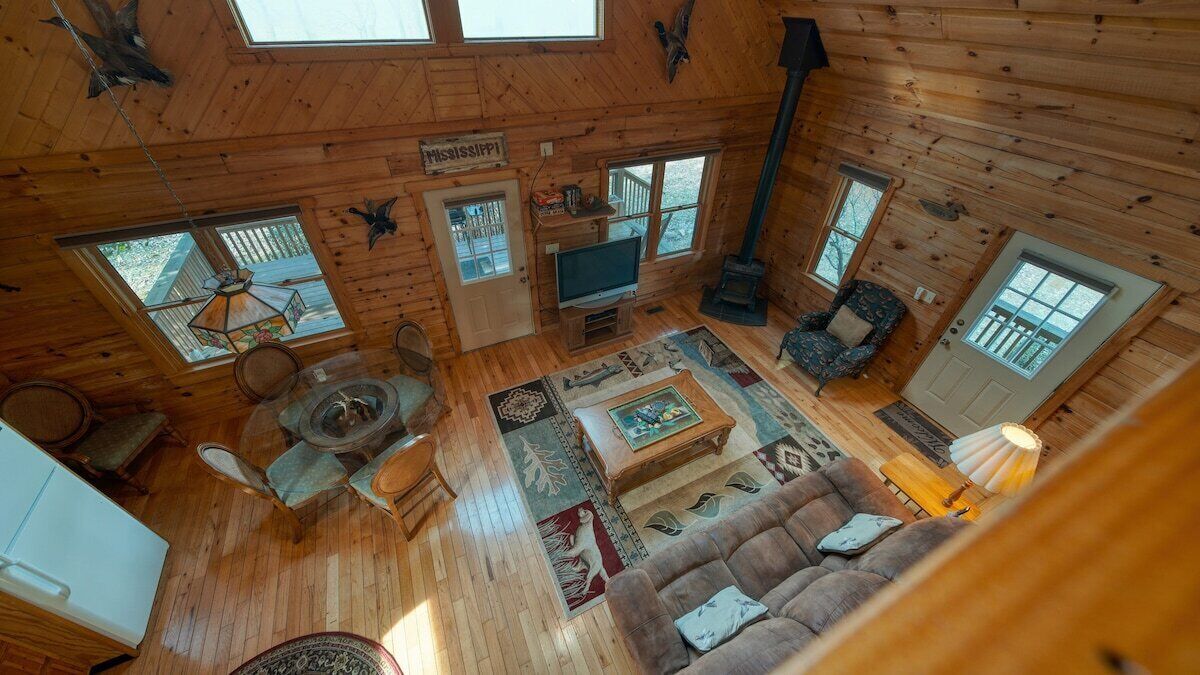 L’intérieur chaleureux d’un chalet avec un plancher en bois, un téléviseur, une cheminée et une porte portant l’inscription « Mississippi ».