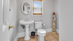 A bathroom with a pedestal sink, toilet, and a window with blinds.