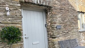 A stone building with a white door, a small plant, and a bench outside.