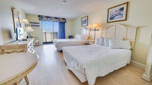 A hotel room with two beds, a desk, a chair, a balcony, and a view of the sea. - Beautiful High-Floor - Ocean Views Newly Renovated (Myrtle Beach)