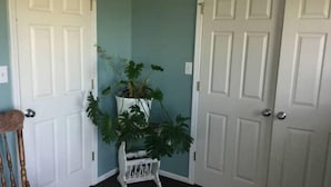 Um corredor com duas portas brancas, um banco branco e um vaso de planta.