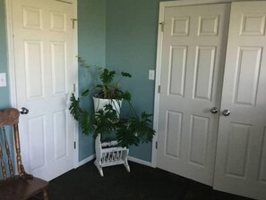 Un couloir avec deux portes blanches, un banc blanc et une plante en pot.
