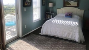 Quarto com cama, janela, porta e vista para o exterior.