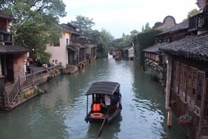 Ein schmaler Wasserweg, gesäumt von traditionellen Gebäuden mit Holzstegen und Booten.
