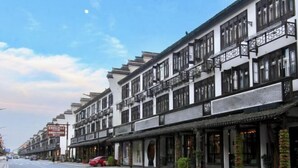 A row of traditional-style buildings with multiple stories, featuring balconies and large windows. - The 2 90's Guys Inn (Tongxiang)