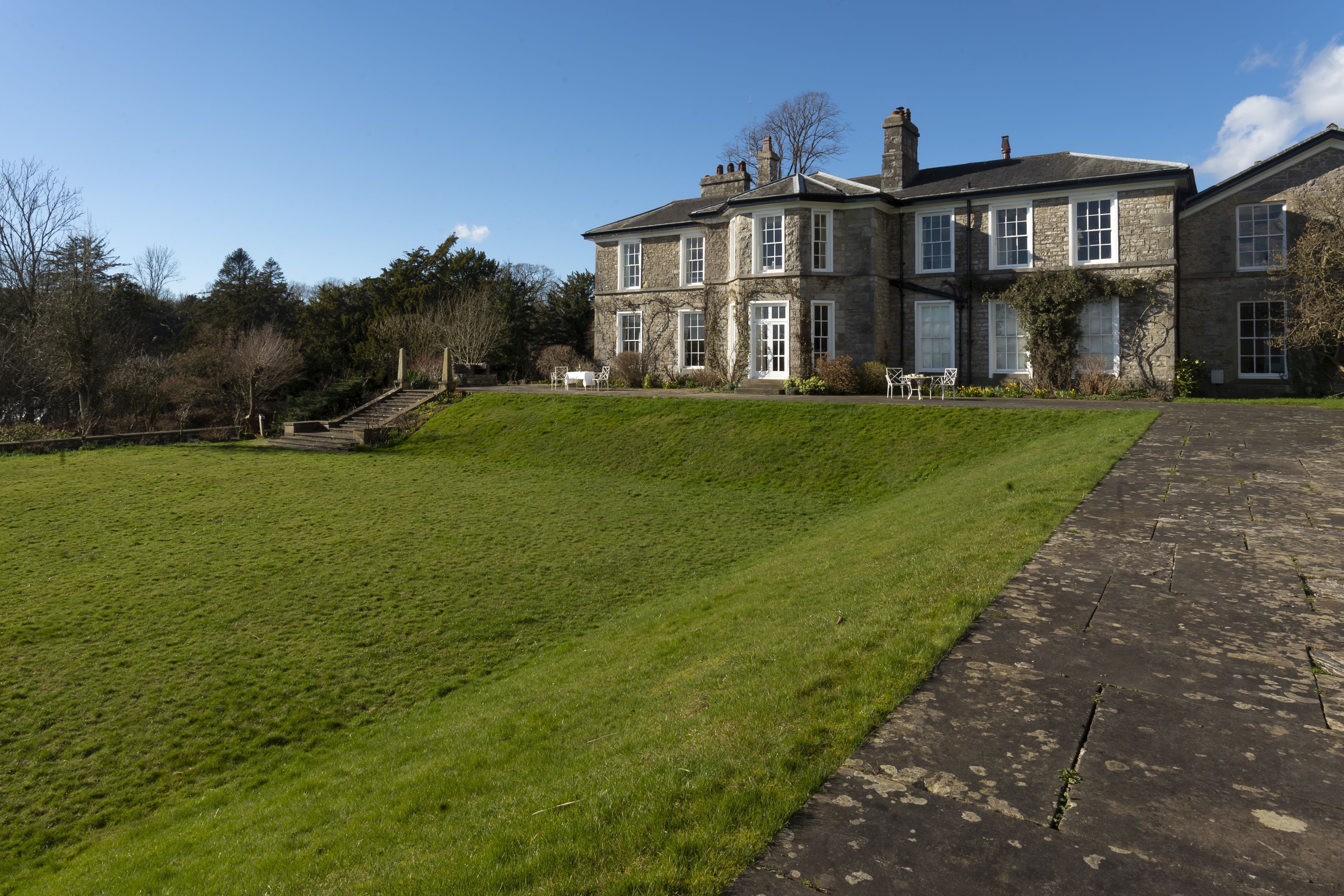 A large stone building with a well-maintained lawn and a paved walkway.