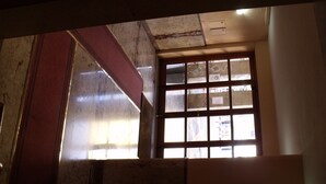 Een kamer met een groot raam, zichtbare balken in het plafond en een gedeeltelijk zicht op een deur.