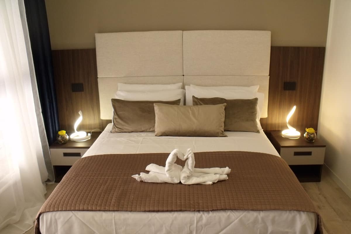 Ein Hotelzimmer mit einem großen Bett, zwei Nachttischen und einem Beistelltisch mit einer Lampe.