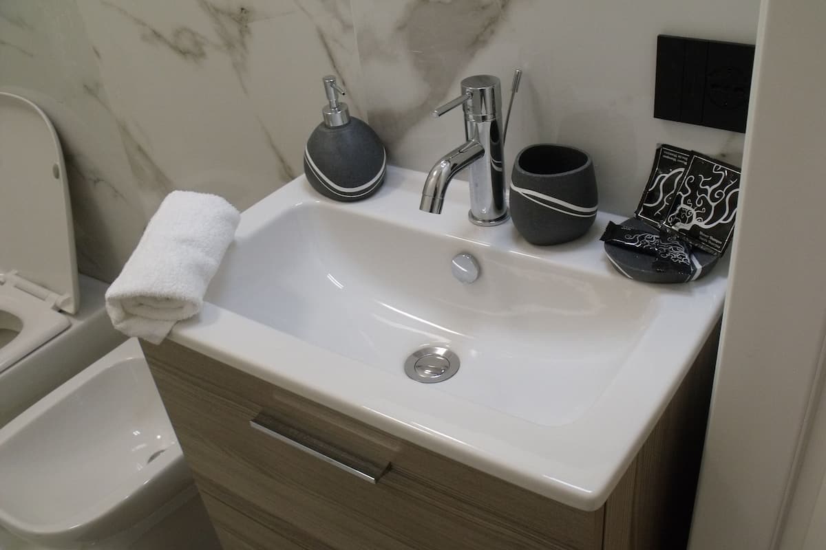 Ein Badezimmer mit einem weißen Waschbecken, einem Handtuch, einem Bidet und einer Marmorwand.