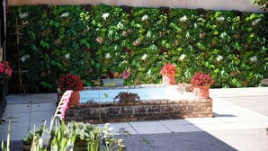 A garden with a water feature, potted plants, and a wall covered in greenery. - LA MAISON ROYALE (Pesmes)