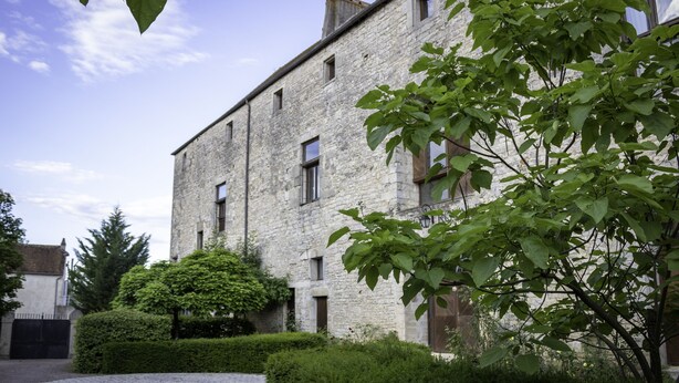 A stone building with multiple windows and a well-maintained garden with hedges and trees. - LA MAISON ROYALE (Pesmes)