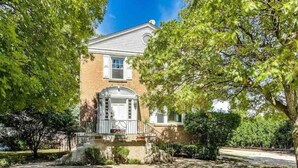 A two-story brick house with a front porch, a garage, and a well-maintained lawn. - Sleepy Sanctuary  (Evanston)
