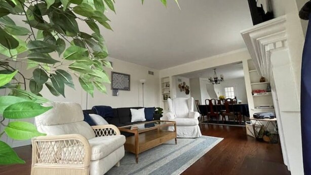 A living room with a sofa, armchair, and coffee table. There is a dining area in the background with a chandelier. - Sleepy Sanctuary  (Evanston)