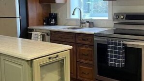 A kitchen with wooden cabinets, a stainless steel microwave, and an oven. - Sleepy Sanctuary  (Evanston)