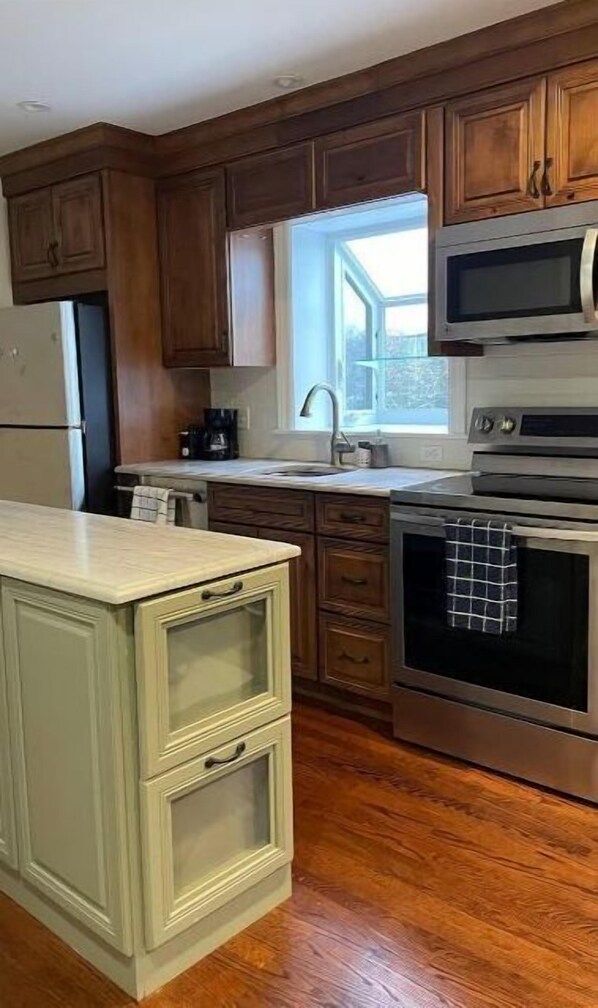 A kitchen with wooden cabinets, a stainless steel microwave, and an oven. - Sleepy Sanctuary (Evanston)
