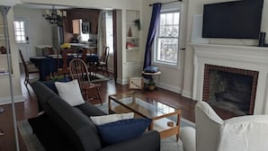 A living room with a sofa, coffee table, fireplace, TV, and a dining area with chairs and a table. - Sleepy Sanctuary  (Evanston)