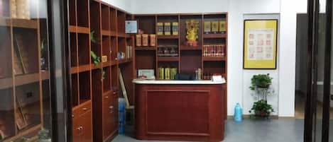 A reception area with a wooden desk, shelves with books, and a framed picture on the wall.