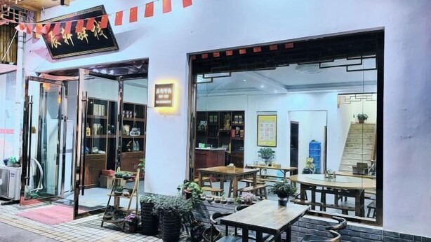 A restaurant with outdoor seating, a glass door entrance, and a sign above the door. - Chen Xuan Yi Zhai (Jiu Hua Mountain Tourist Service Center Store) (Qingyang)