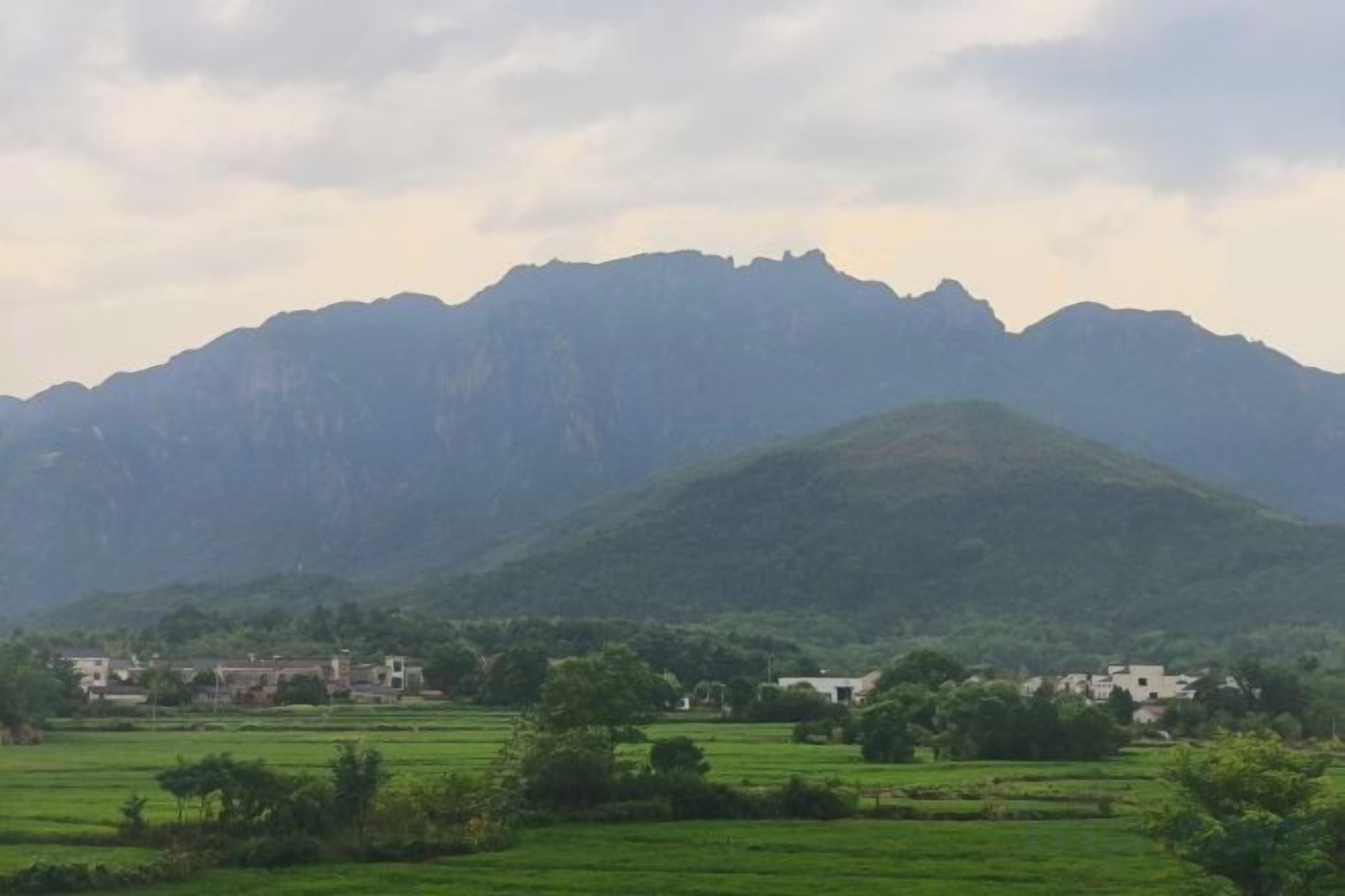 A mountainous landscape with a village in the foreground and a clear sky above.