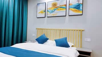 Un dormitorio con una cama, ropa de cama azul y blanca, un cabecero de madera y tres cuadros en la pared.