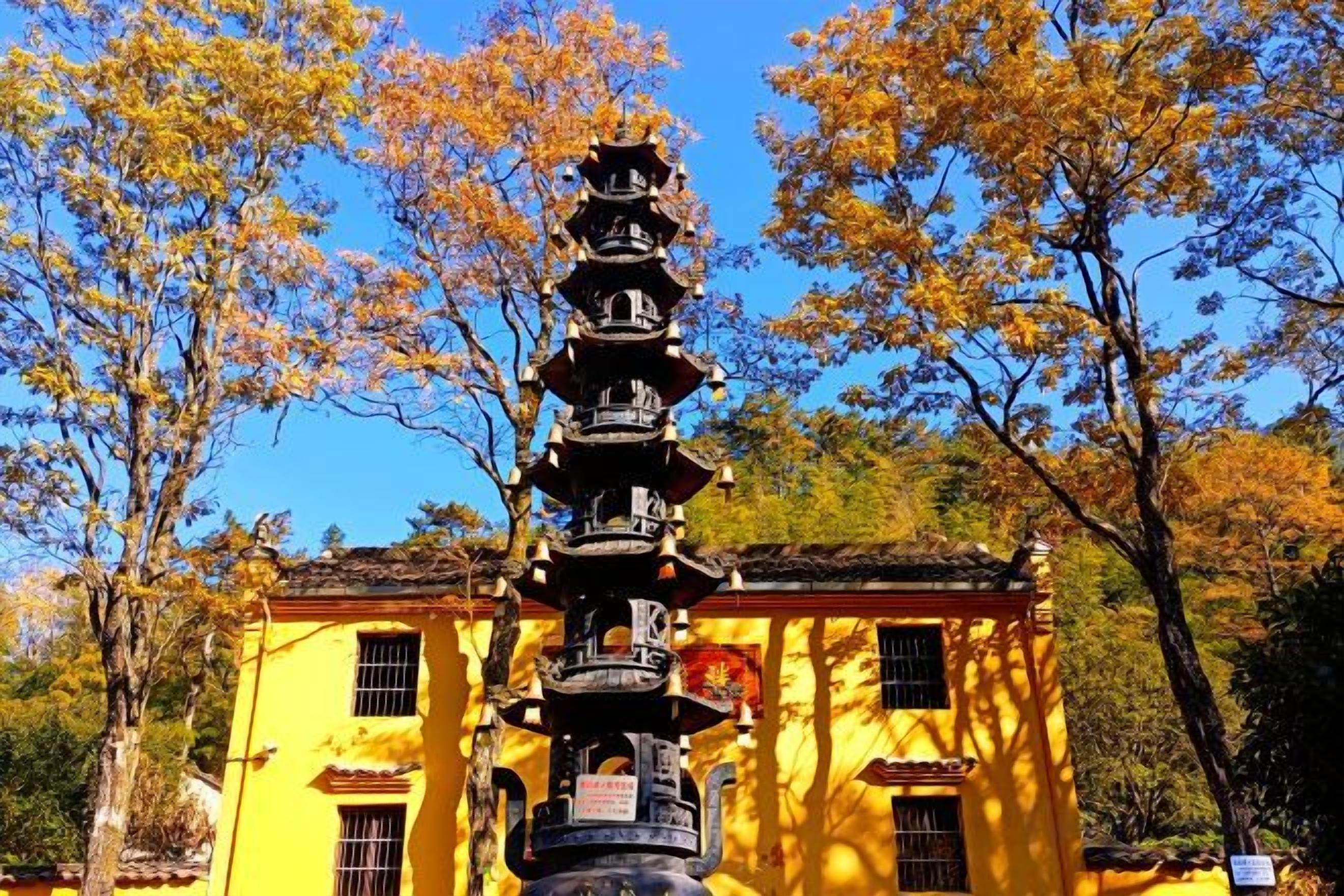 A traditional multi-tiered structure in front of a yellow building with windows.