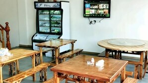 A room with wooden tables and benches, a refrigerator, and a television mounted on the wall. - Chen Xuan Yi Zhai (Jiu Hua Mountain Tourist Service Center Store) (Qingyang)