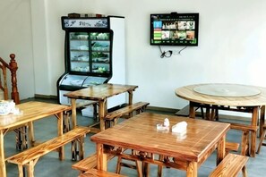 A room with wooden tables and benches, a refrigerator, and a television mounted on the wall. - Chen Xuan Yi Zhai (Jiu Hua Mountain Tourist Service Center Store) (Qingyang)