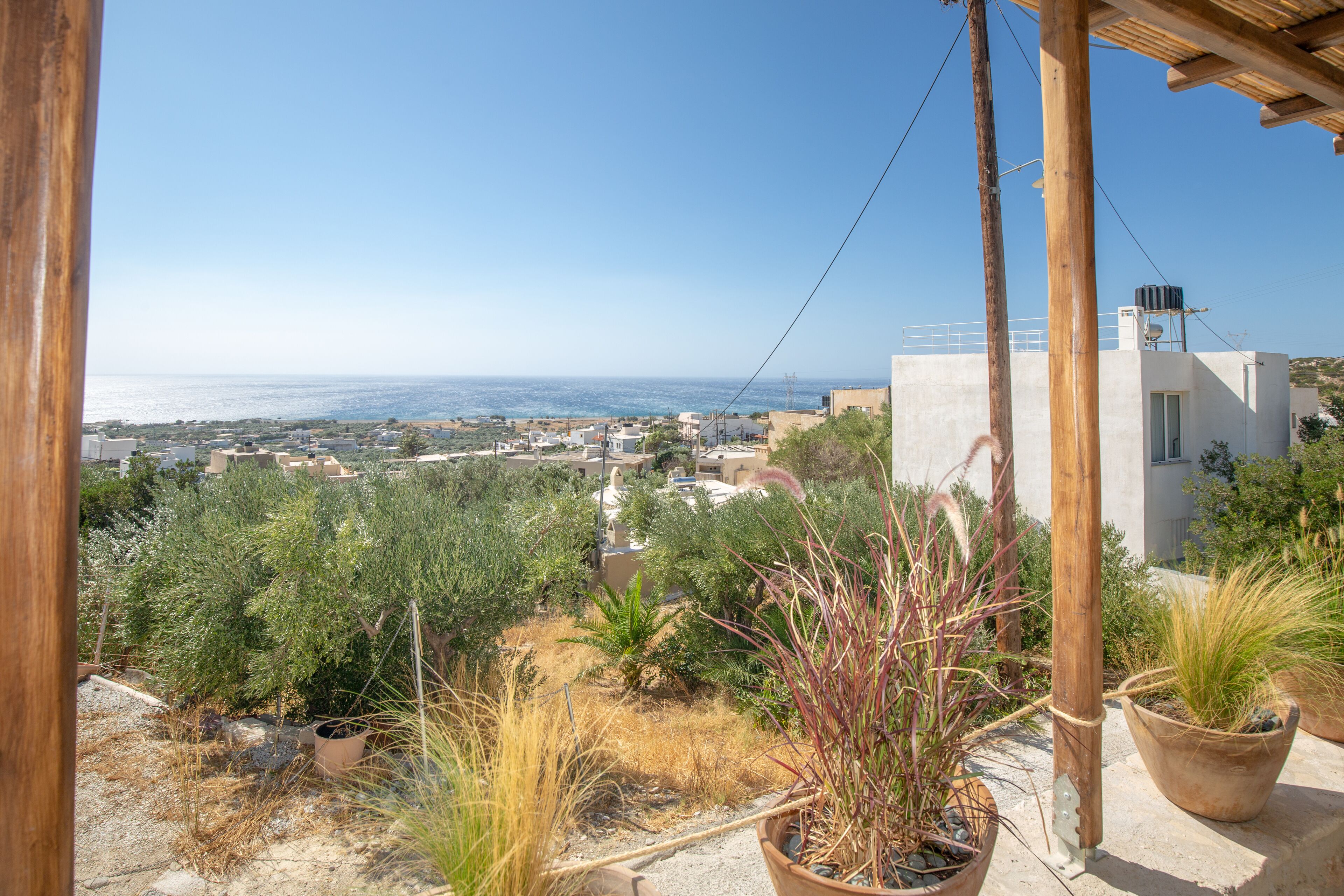 Un jardín en la azotea con plantas en macetas, con vistas a un pueblo costero.