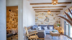 Ein gemütliches Wohnzimmer mit einer Steinwand, einer Sofagarnitur, einem Holzstuhl und einem Couchtisch.