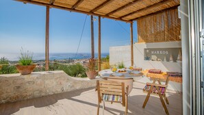 Eine Terrasse mit Esstisch, Holzstuhl und Staffelei mit einem farbenfrohen Gemälde.
