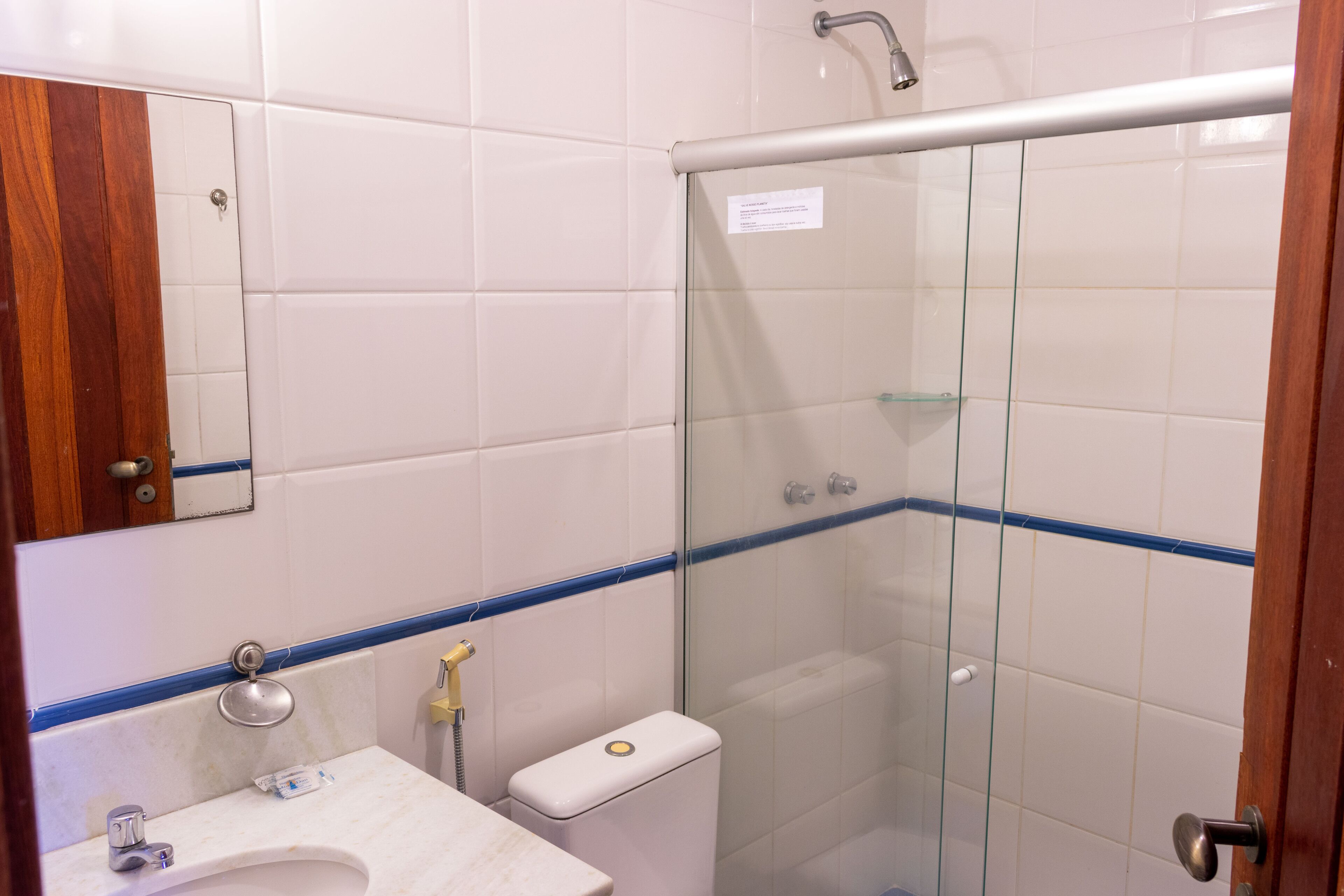 A bathroom with a sink, mirror, toilet, and glass-enclosed shower.